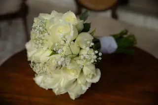 Illustration: A bouquet of white roses and baby's breath rests on a wooden table.