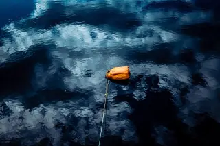 Illustration: An orange plastic jug floats as a buoy tied to a rope in dark rippling water.