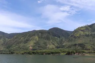 Illustration: A calm lake surrounded by green hills with small wooden boats on the water.