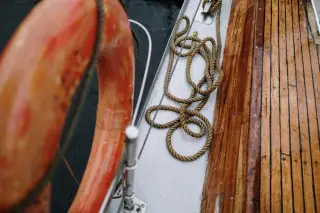 Illustration: A wooden boat deck with an orange lifebuoy and coiled rope beside the water.