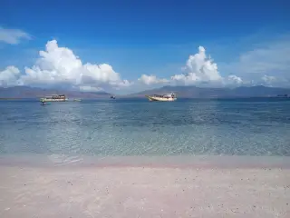 Illustration: Boats anchored in clear blue waters off a pinkish sandy beach under a sunny sky.