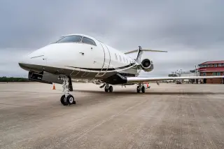 Illustration: A private jet parked on a concrete tarmac under an overcast sky.