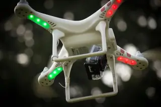 Illustration: A white quadcopter drone carrying an action camera hovers against a dark, blurry background.