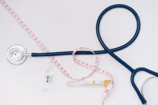 Illustration: A stethoscope, measuring tape, ampoule, and test tube laid out on a white background.