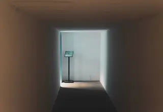 Illustration: A quiet, empty corridor with light at the end and a small informational sign stand.
